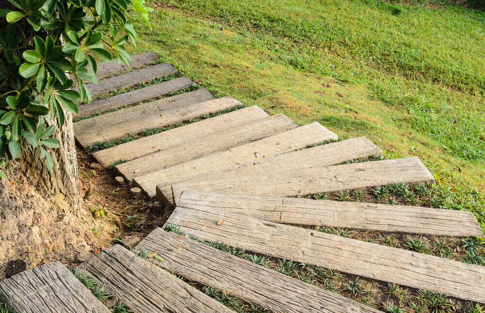 These garden steps are made up of wood planks, making a curve around the bend downwards on the green grassy slope